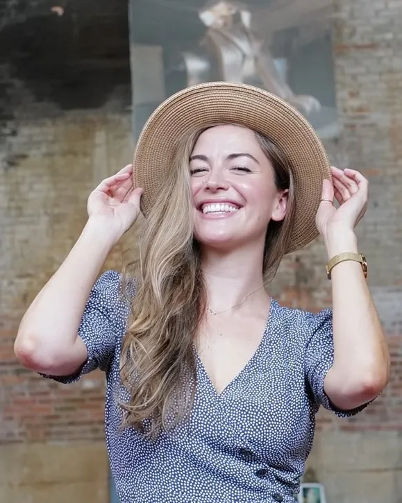Jessica laughing, holding the brim of her hat